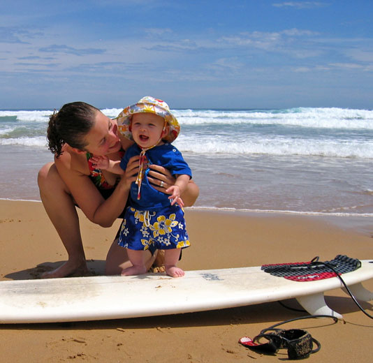 Mother and Son on the beach with a surfboard