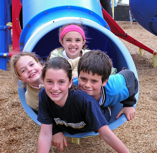 4 kids coming down the playground slide